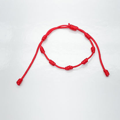 7 knot red string bracelet against white background